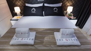Een hotelkamer met een groot bed, twee kussens met een logo, twee nachtkastjes met lampen en twee handdoeken met de naam van het hotel.