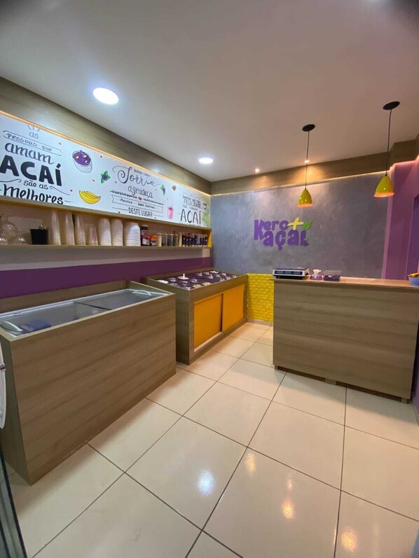 A clean, modern cafe interior with a counter, seating area, and a wall with text and graphics. - Pousada Leda Rafael (Joao Camara)