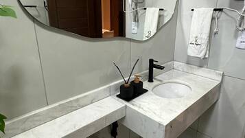 Un baño moderno con inodoro blanco, lavamanos y espejo.