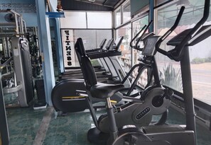 A gym with multiple treadmills, weight machines, and a mirrored wall.