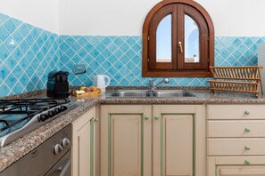 Een keuken met een gasfornuis, een koffiezetapparaat en een spoelbak.