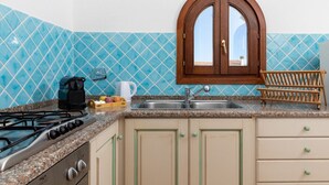 Una cocina con estufa a gas, cafetera y lavamanos.