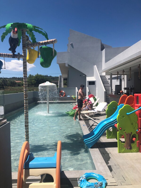 A pool area with slides, a water feature, and lounge chairs. - Amaltheia Beach Front Houses (Zakynthos)