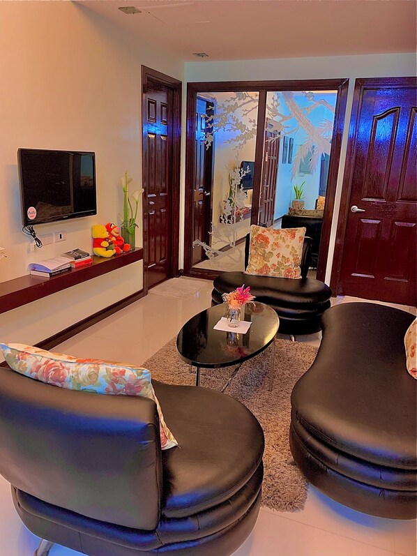 Relax in this stylish living room with a flat-screen TV, comfortable sofa, and a balcony with a view.