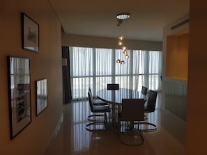 Enjoy meals in this stylish dining area with a round table and four chairs, surrounded by large windows and framed artworks.