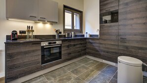 Een moderne keuken met donker houten kastjes, een ingebouwde oven en een raam boven de gootsteen.