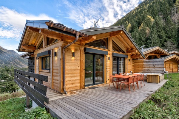 Kitchen opens onto deck with outdoor dining furniture and hot tub