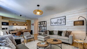 Un salon moderne comprenant un canapé, des fauteuils, une table basse et un coin repas avec des chaises et une table.