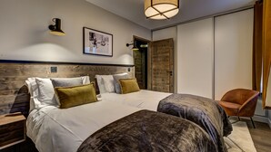 Un dormitorio con una cama grande, cabecera de madera, una mesita auxiliar, una silla y una lámpara colgante.