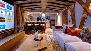 Un salon chaleureux avec un plafond en bois, un canapé et un écran de télévision affichant une sélection de films.