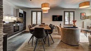 Una cocina moderna con armarios de madera oscura, horno empotrado y comedor con mesa y sillas de madera.