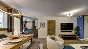Un salon moderne comprenant un coin repas, un canapé confortable, un téléviseur et une porte en bois.