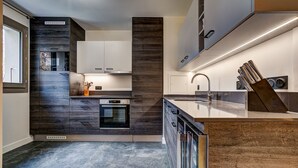 Une cuisine moderne avec des meubles de couleur bois foncé, un four encastré et un évier en acier inoxydable.