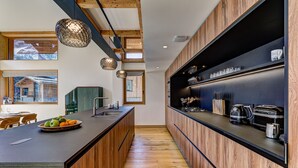 Eine moderne Küche mit Holzschränken, einer zentralen Kochinsel und Blick auf eine Bergliebungshütte.
