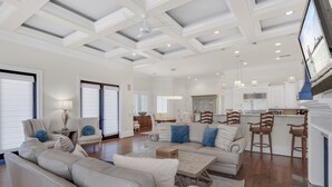 A spacious living room with a high ceiling, a large sofa, a coffee table, and a television mounted on the wall. - Minutes to Multiple Beach Access Points + Private Pool + Backyard Oasis (Santa Rosa Beach)