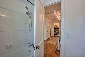 A bathroom with a bathtub, shower, and white tiled walls.