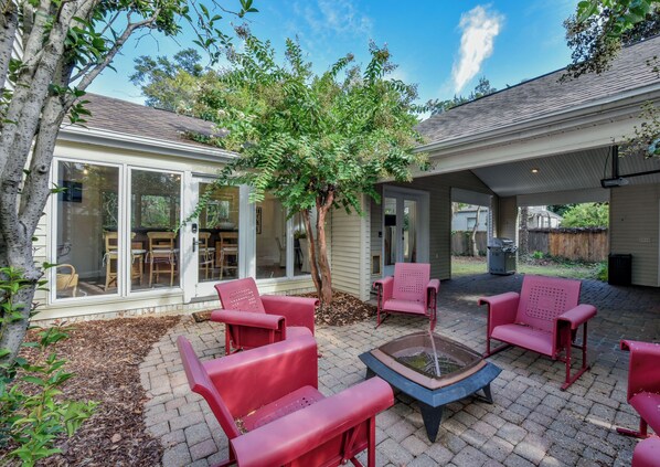 A patio area with red chairs, a fire pit, and a covered seating area.