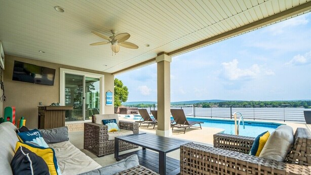 A covered outdoor area with wicker furniture, a pool, and a view of the water.