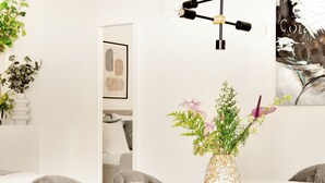 A dining area with a round table, a vase with flowers, and a slice of cake on a plate. - City 4- Spacious Studio in the Center of Copenhagen (Copenhagen)
