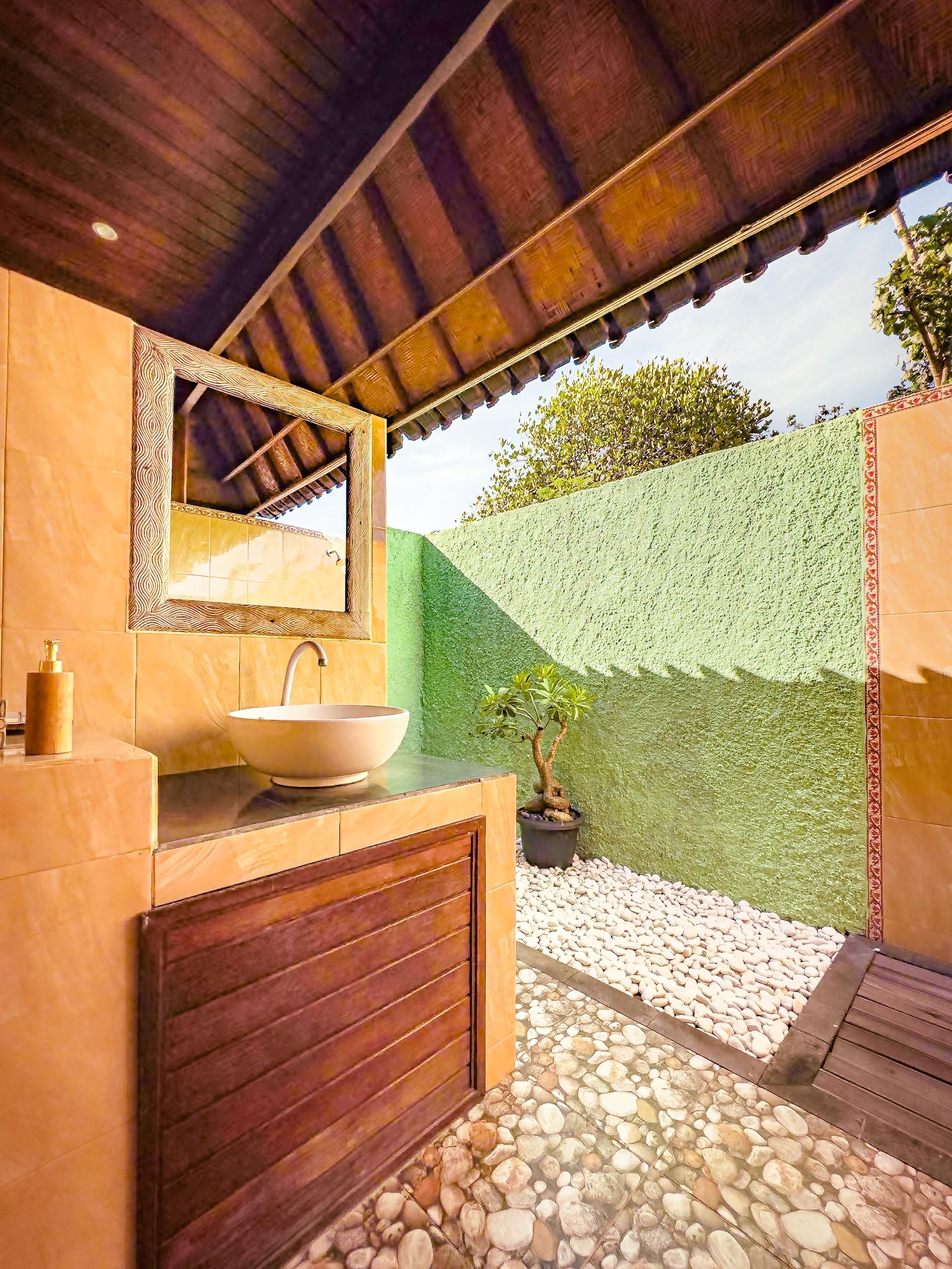 A bathroom with a large sink, wooden vanity, and a small potted plant.