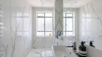 Un baño moderno con un espejo grande, un lavabo blanco y una zona de ducha.