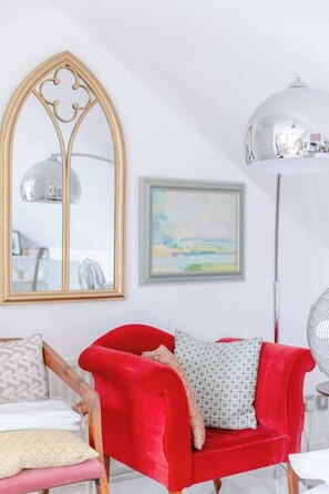 Relax in a clean and contemporary living space with a stylish armchair, elegant mirror, and comfortable seating area.