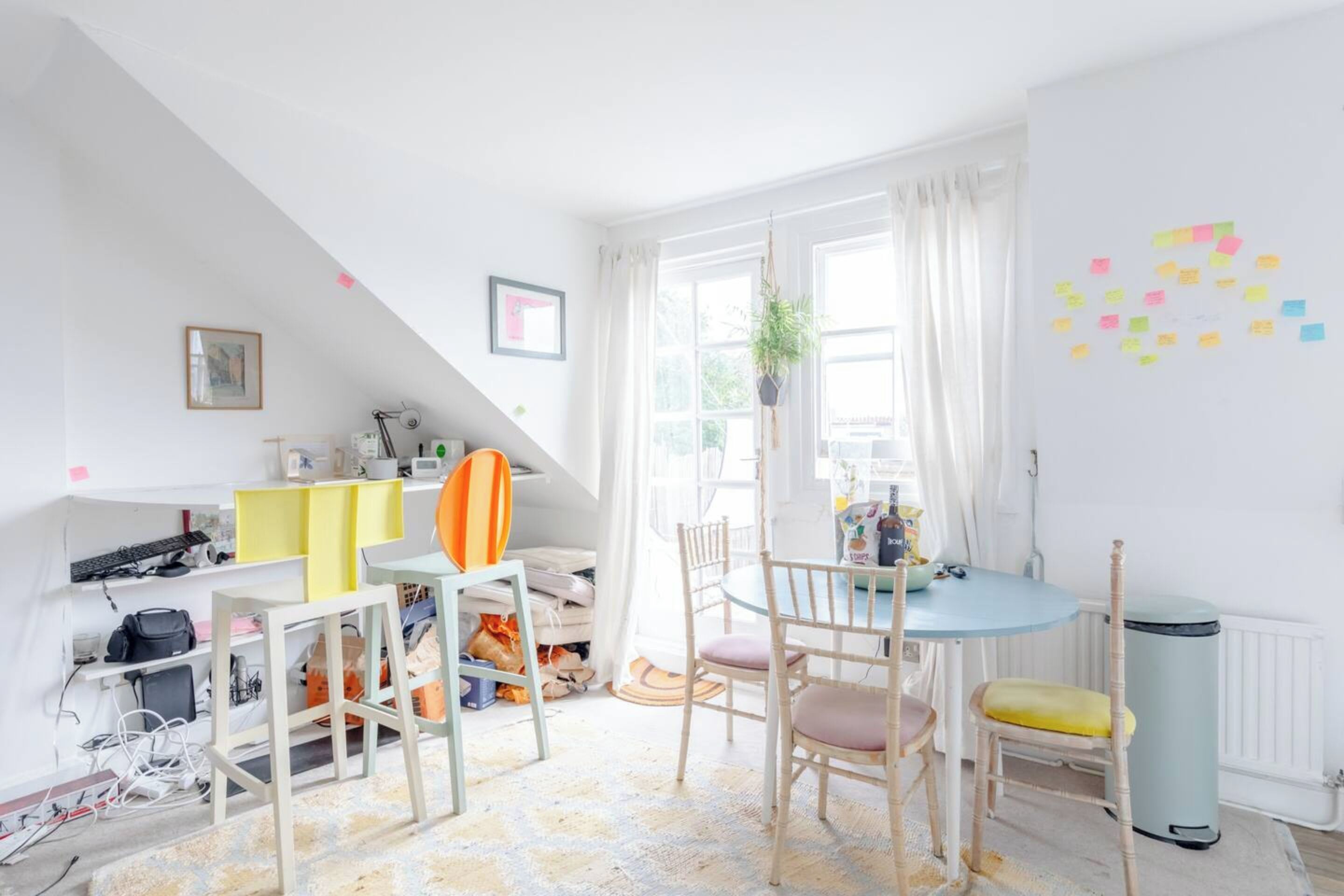 A bright, well-lit room with a dining table, chairs, and a small kitchen area.