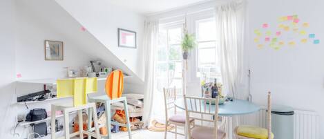 A bright, well-lit room with a dining table, chairs, and a small kitchen area.