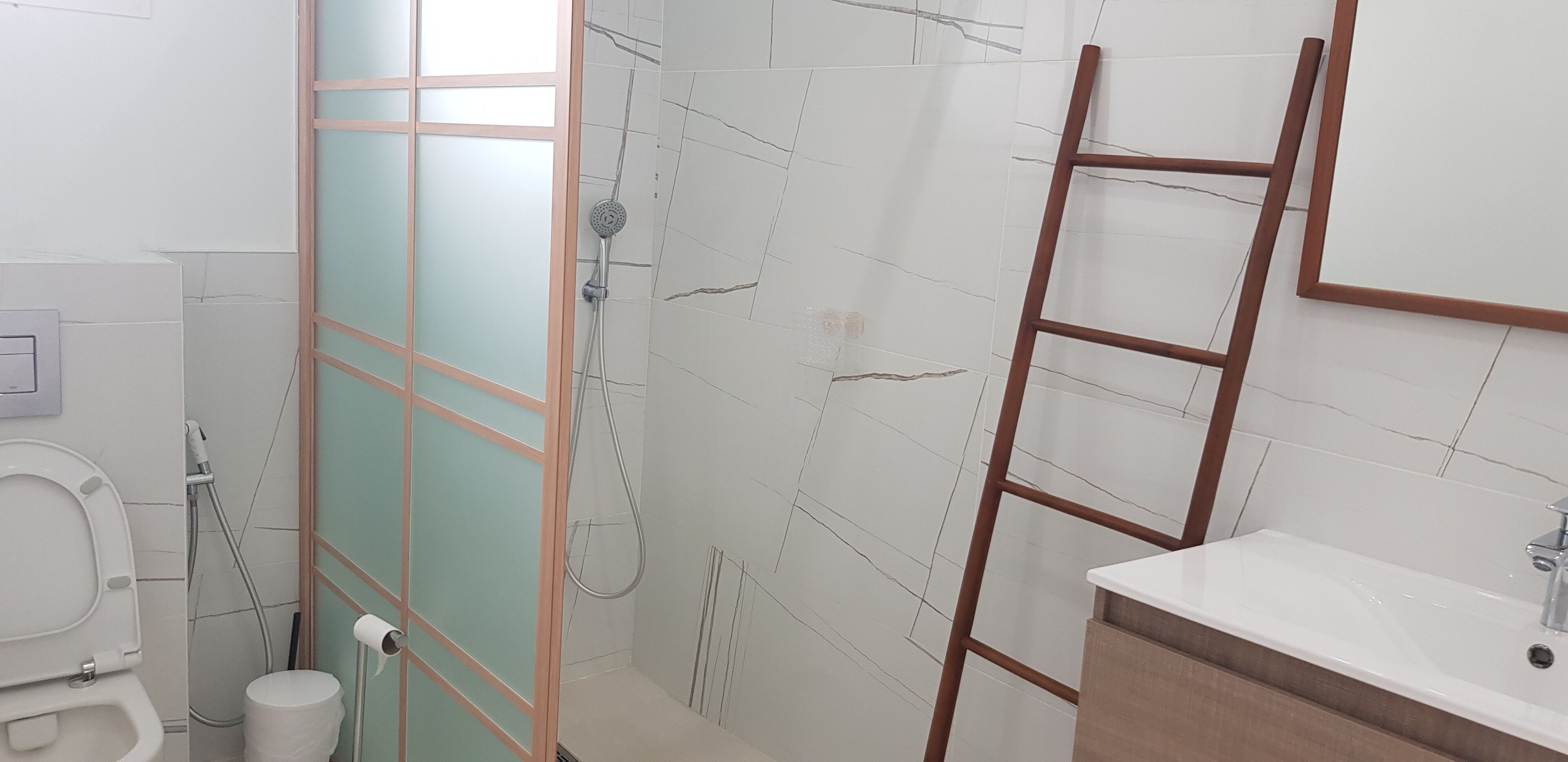 A bathroom with a toilet, a shower with a glass door, and a sink with a mirror.