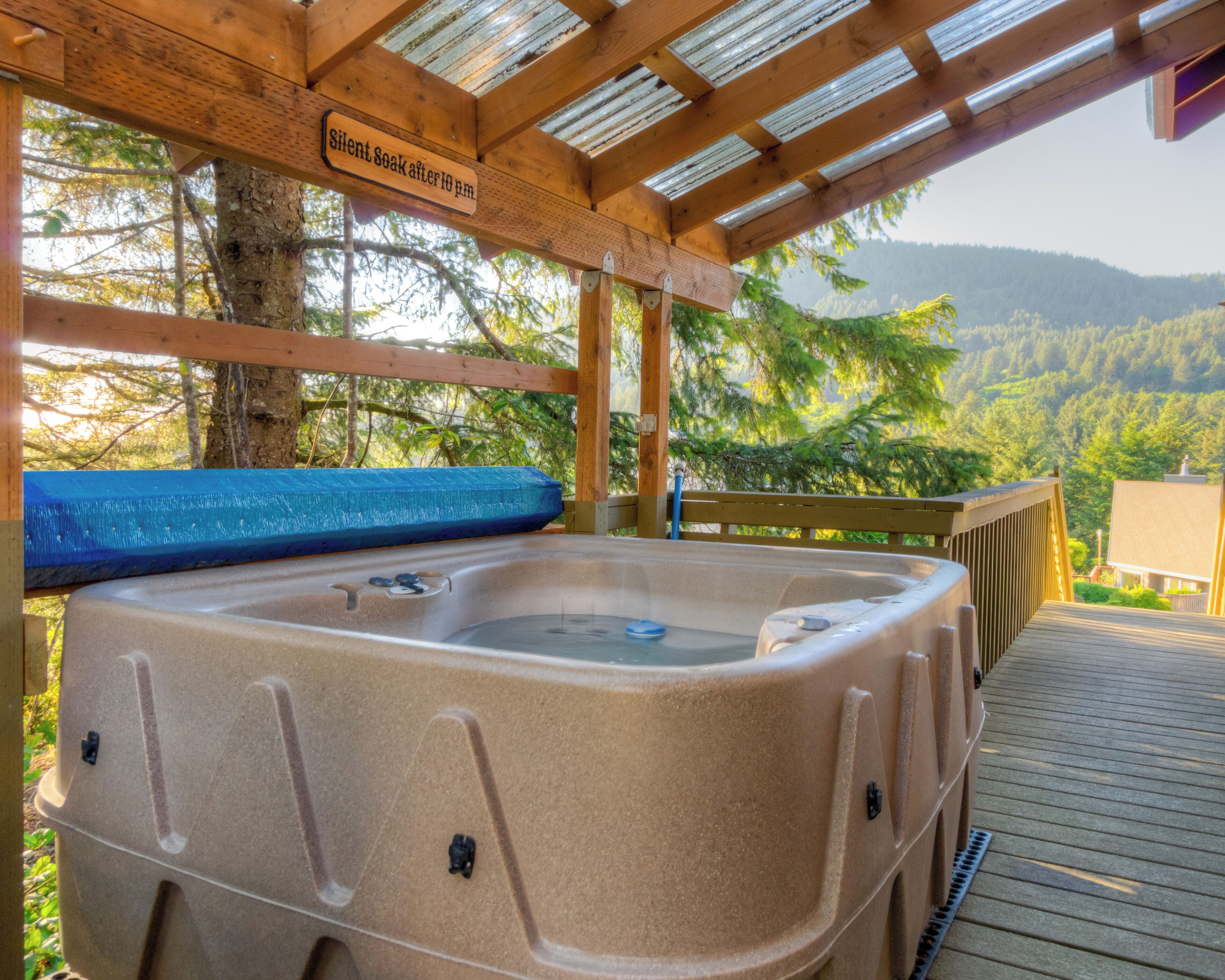 Un bain à remous installé sous une pergola en bois, avec un panneau indiquant qu’il est interdit de faire du bruit après 22 heures.