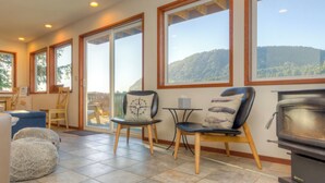 A cozy living room with a fireplace, large windows, and a view of the outdoors. - Hot tub, foos ball, airhockey, dogs ok, 4 bedroom,Starlight Hideaway MCA#1358 (Manzanita)