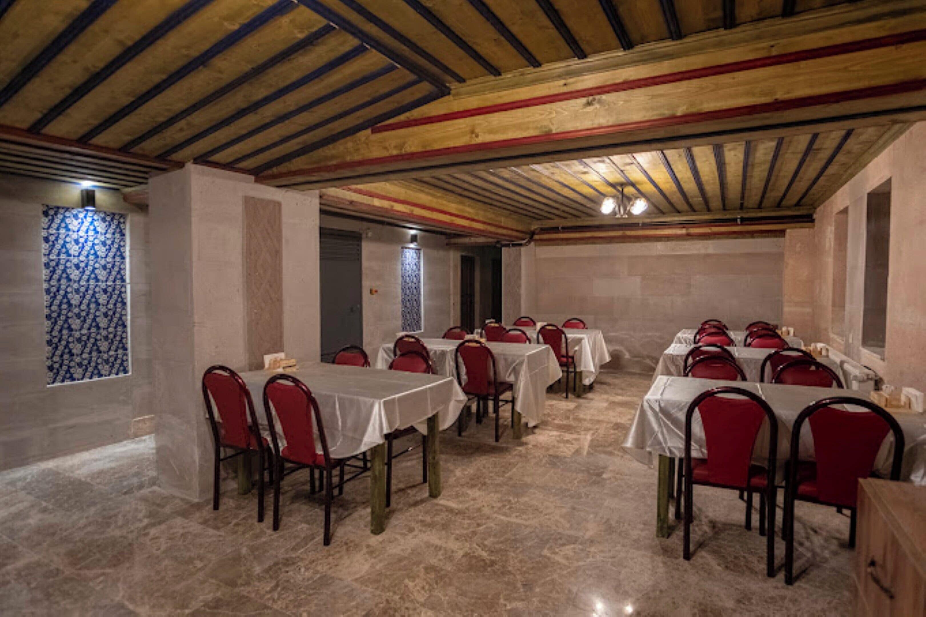 Un espace repas avec des tables et des chaises, un sol carrelé et un plafond en bois.