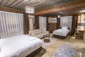 Una habitación de hotel con dos camas, un sofá, una mesita y un tapete estampado.