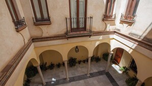 A courtyard with arches, potted plants, and a tiled floor. - Centro Histórico de Sevilla XIX (Sevilla)
