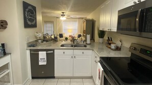 A modern kitchen with white cabinets, a stainless steel microwave, and a dishwasher. - Gameday Condo 2 miles from Campus!   (Auburn)