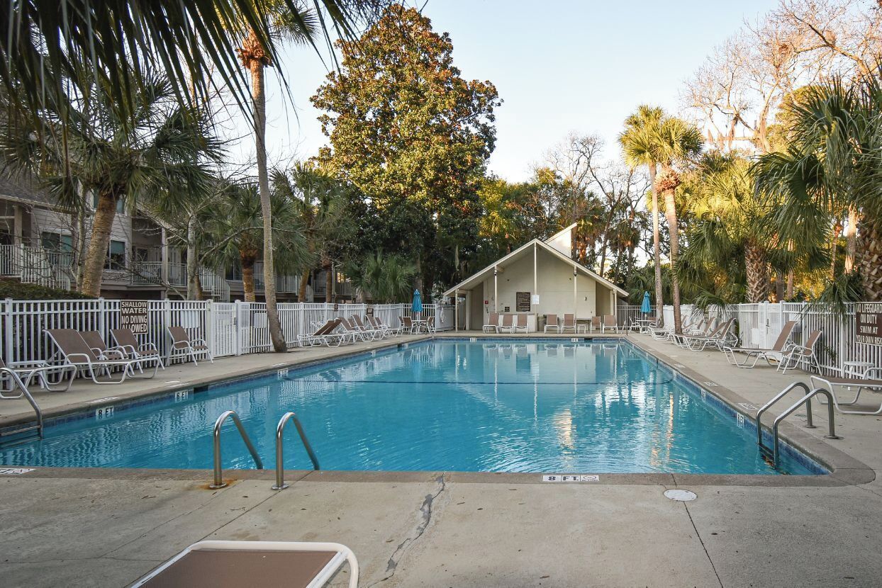 A swimming pool with lounge chairs and a small building in the background.