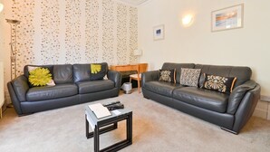 A living room with two black leather sofas, a small table, and a patterned wallpaper. - Real hidden gem - Free all Island parking permit (Ventnor)
