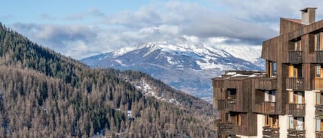 A modern building with balconies overlooking a snowy mountain range.