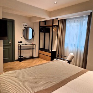 A hotel room with a bunk bed, a desk with a mirror, a wardrobe, and a large window with curtains. - In The Middle Hotel (Antalya)