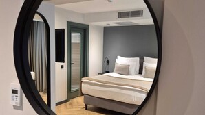 Une chambre à coucher avec un lit, un miroir, une porte et un interrupteur.