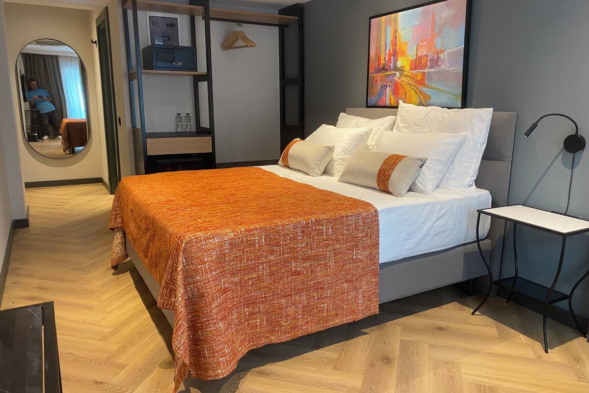 Une chambre à coucher moderne avec un lit, une table de chevet, un miroir et un tableau au mur.