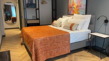 A modern bedroom with a bed, a bedside table, a mirror, and a painting on the wall.