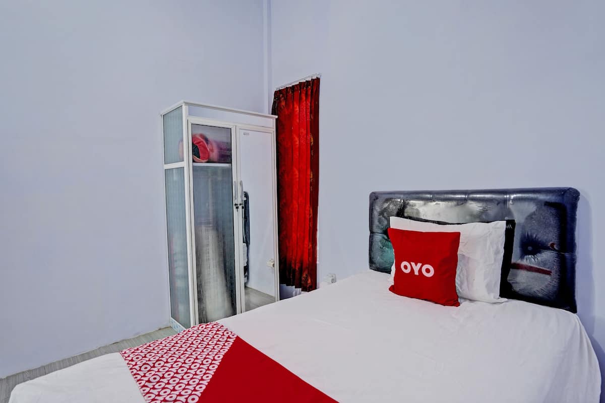 A hotel room with a bed, a wardrobe, and a red curtain.