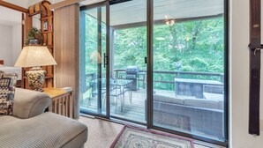 Ein Zimmer mit einer großen Schiebeglastür, die auf eine Terrasse mit Grill führt.