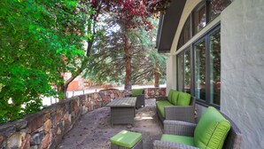 An outdoor patio area with wicker furniture, stone walls, and large windows. - Fully Renovated 2 Bedroom in Arrowhead Village! 2 Condo by RedAwning (Edwards)