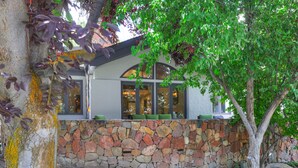 A modern house with a stone wall, large windows, and a tree in the yard. - Fully Renovated 2 Bedroom in Arrowhead Village! 2 Condo by RedAwning (Edwards)