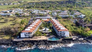 A resort with a long building along the coastline, a swimming pool, and a rocky shoreline. - Big Island Casa De Emdeko A308 1 Bedroom Condo (Kailua-Kona)