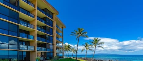 A multi-story hotel with balconies overlooking a beach and ocean.