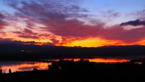 Un coucher de soleil sur un lac, avec des montagnes en arrière-plan.