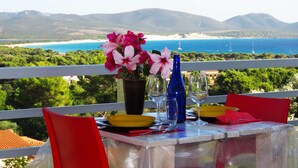 Une table dressée pour deux personnes, avec vue sur la mer et les montagnes.